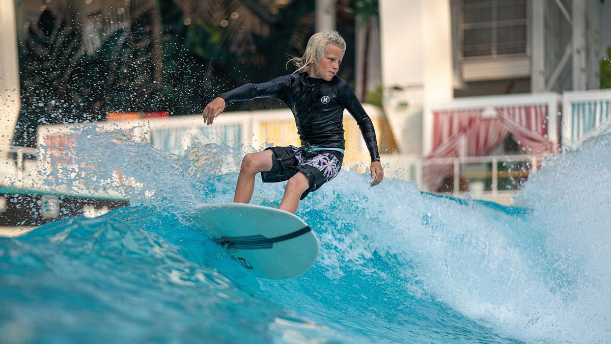 child on surfboard riding wave at Surf Simulator at DreamWorks Water Park in New Jersey, USA